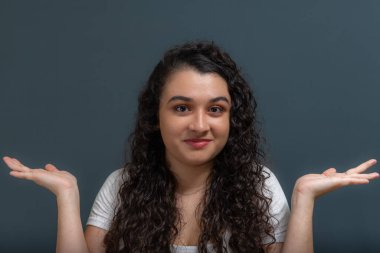 Neşeli genç ve güzel bir kadın kollarında jestlerle neler olduğunu soruyor. Gri arkaplanda izole.