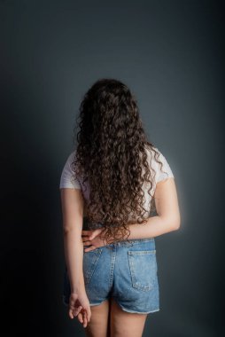 Siyah saçlı, beyaz gömlek giyen güzel bir genç kadın profili. Gri arkaplan. 