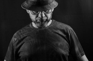 Şapka ve gözlük takan bir adamın siyah beyaz portresi. Siyah arkaplanda izole.