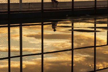 Salvador, Bahia, Brezilya - 05 Aralık 2021: Salvador, Bahia 'da Rio Vermelho plajında günbatımına karşı egzersiz yapan insanların siluetinin yansıması.