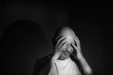 Siyah ya da beyaz, eli yüzü siyah arka planda olan ya maddi sorunları olan ya da yalnızlık çeken orta yaşlı bir adamın siyah ve beyaz portresi.