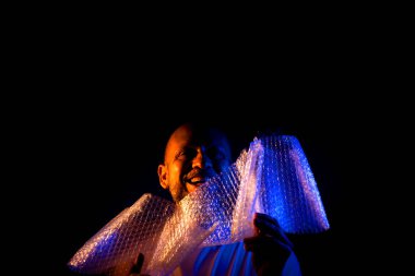 Orta yaşlı bir adam, komik, neşeli, baloncuklarla dolu plastik bir çantayla oynayan. Eğlenceli konsept.