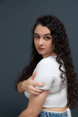 Beyaz gömlek giyen, el ele tutuşan neşeli, güzel bir genç kadın. Gri arka plana karşı. gençlik kavramı