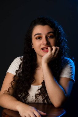 Ağzında eli olan neşeli, genç ve güzel bir kadın. Gri arkaplan.