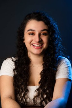 Genç ve güzel bir kadın mutlu bir şekilde gülümsüyor ve kameraya bakıyor. Gençlik konsepti. Gri arkaplan.