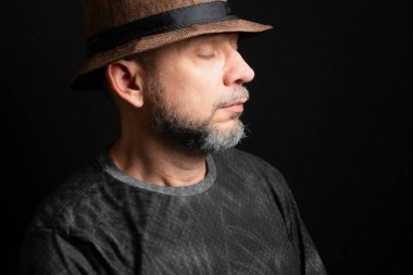 Şapkalı adam. Sağ tarafa bakıyor. Siyah arkaplanda izole.