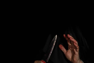 Siyah arka planda sahte kanla boyanmış, el ele tutuşan bıçak. Bıçak saldırısı konsepti.