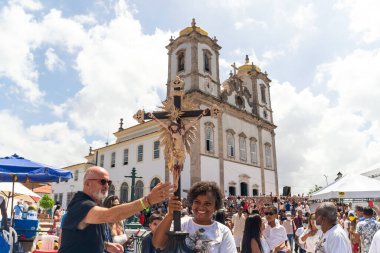 Salvador, Bahia, Brazil - January 06, 2023: Catholics touching the image of Jesus Christ during mass at Senhor do Bonfim church, in the background, in Salvador, Bahia. clipart