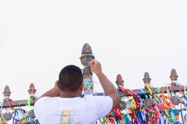 Salvador, Bahia, Brazil - January 06, 2023: Catholic man placing ribbon on the railing of Senhor do Bonfim church during mass. City of Salvador, Bahia.