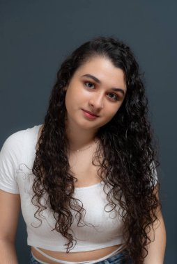 Close-up vertical portrait of young beautiful woman looking at camera. Against gray background.