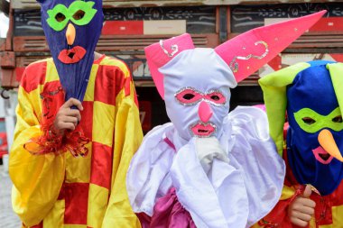 Maragogipe, Bahia, Brazil - February 27, 2017: Three people dressed in colorful costumes and masks at the carnival parade in Maragojipe, Bahia.