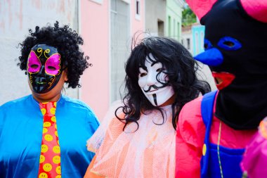 Maragogipe, Bahia, Brazil - February 27, 2017: Three people dressed in colorful costumes and masks at the carnival parade in Maragojipe, Bahia.