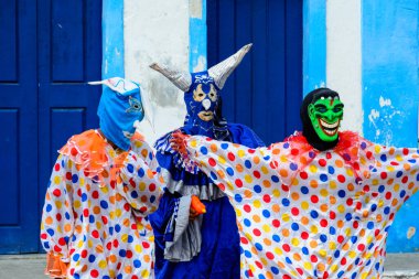 Maragogipe, Bahia, Brazil - February 27, 2017: Three people dressed in colorful costumes and masks at the carnival parade in Maragojipe, Bahia.