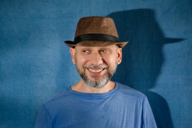 Smiling man wearing hat. Isolated on blue background with shadow.