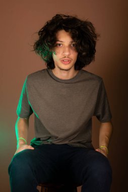 Yakışıklı ve mutlu genç adam oturuyor. İzole Bisque arkaplanı.