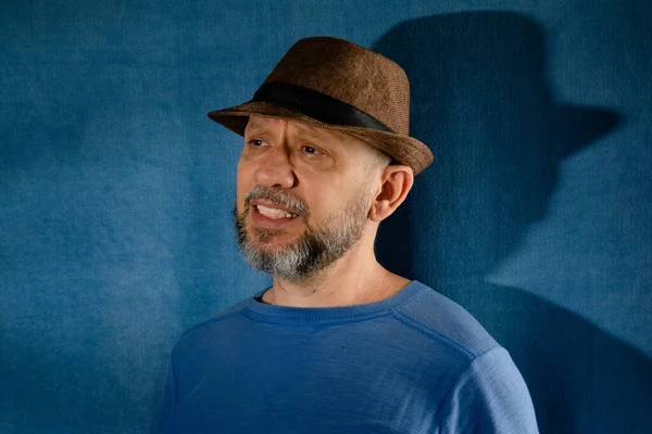 Smiling man wearing hat. Isolated on blue background with shadow.