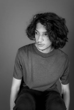 Black and white studio portrait of a young man beautiful. Isolated against Bisque background.