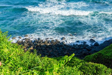 Ocean seen from above with trees and rocks. Postcard from Salvador, Brazil.