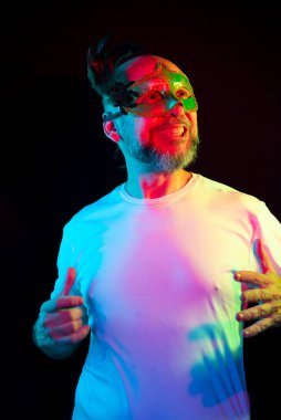Studio portrait of bald man, bearded, wearing carnival mask. Isolated in the black background.