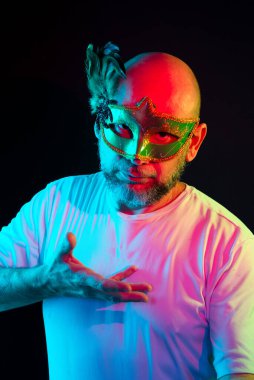 Man portrait, bald, wearing carnival mask. Making gestures with your hands. Isolated in the black background.