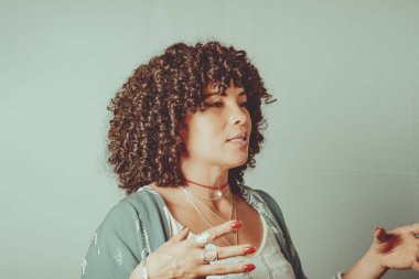 Portrait of cheerful, smiling woman with curly hair. Isolated on light green background.