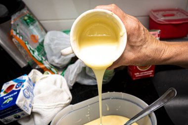 Krema, peynirli kek yapmak için plastik bir kaba dökülüyor. Aile gastronomisi.