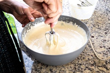 Cheesecake malzemelerini hazırlamak için elektrikli mikser kullanılıyor. Aile gastronomisi.