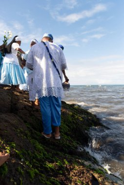 Salvador, Bahia, Brazil - February 02, 2023: Candomble people are on the rocks of Rio Vermelho beach, offering gifts to Yemanja. Salvador, Bahia.