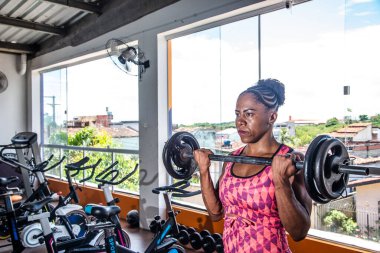 Spor salonunda ağırlık kaldıran kararlı bir kadın. Kolları güçlendiriyorum..