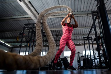 Woman doing training with naval rope. Abdominal strengthening and muscular endurance.