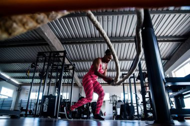 Woman doing training with naval rope. Abdominal strengthening and muscular endurance.