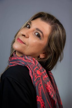 Güzel, neşeli bir kadın kameraya bakıyor. Gri arkaplanda izole.