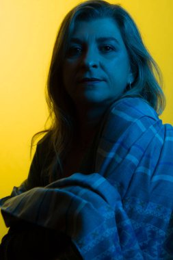 Mavi ışık altında güzel bir kadın portresi. Koyu sarı arka planda izole edilmiş.