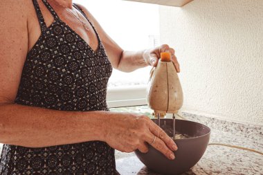 Cheesecake malzemeleri hazırlamak için elektrikli mikser kullanan bir kadın. Aile gastronomisi.