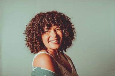 Portrait of cheerful, smiling woman with curly hair. Isolated on light green background.
