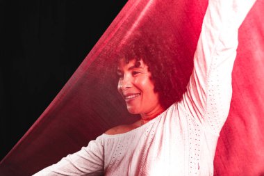 Portrait of a woman with red cloth stretched in front of her face. isolated on black background.