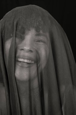 Black and white portrait of a womans face covered with cloth. Isolated on black background.