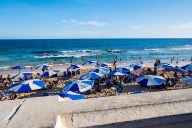 Salvador, Bahia, Brezilya - 22 Ekim 2022: İnsanlar sıcak bir günde Farol da Barra plajında yürüyüp dinleniyorlar. Salvador, Bahia.