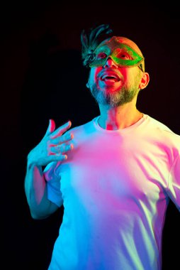 Man portrait, bald, wearing carnival mask. Making gestures with your hands. Isolated in the black background.