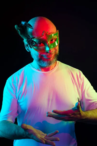 Man portrait, bald, wearing carnival mask, looking at the camera. Isolated in the black background.