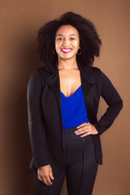 Kahverengi arka planda duran siyah ceketli bir işletmeci kadın. Stüdyo resmi.