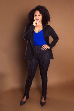 Kahverengi arka planda duran siyah ceketli bir işletmeci kadın. Stüdyo resmi.