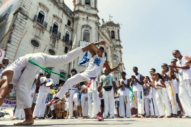 Salvador, Bahia, Brazil - December 08, 2022: People play capoeira during the outdoor mass in honor of Nossa Senhora da Conceicao da Praia, in the city of Salvador, Bahia. clipart