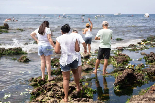 stock image Salvador, Bahia, Brazil - February 02, 2023: People are seen on top of the rocks at Rio Vermelho beach, offering gifts to Yemanja, in Salvador, Bahia.