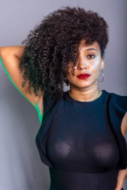 Gri arkaplana karşı duran, kameraya bakan güzel bir genç kadın. Stüdyo resmi