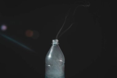 Moving smoke coming out of a plastic bottle. Isolated on black background.