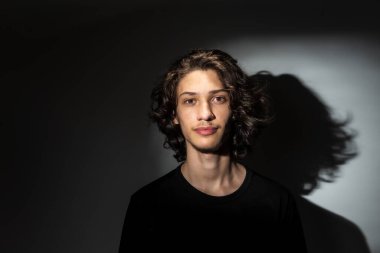 Beyaz arka planda gölgeli uzun saçlı yakışıklı bir adamın portresi..