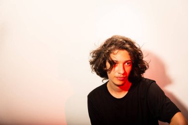 Beyaz arka planda uzun saçlı, yüzünde kırmızı ışık olan yakışıklı bir adamın portresi..