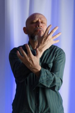 Ayakta duran adam el hareketi yapıyor. Mavi filtreli stüdyo portresi. beyaz perde arkaplanı