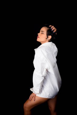 Studio portrait of beautiful young woman wearing white outfit. Isolated on black background.
